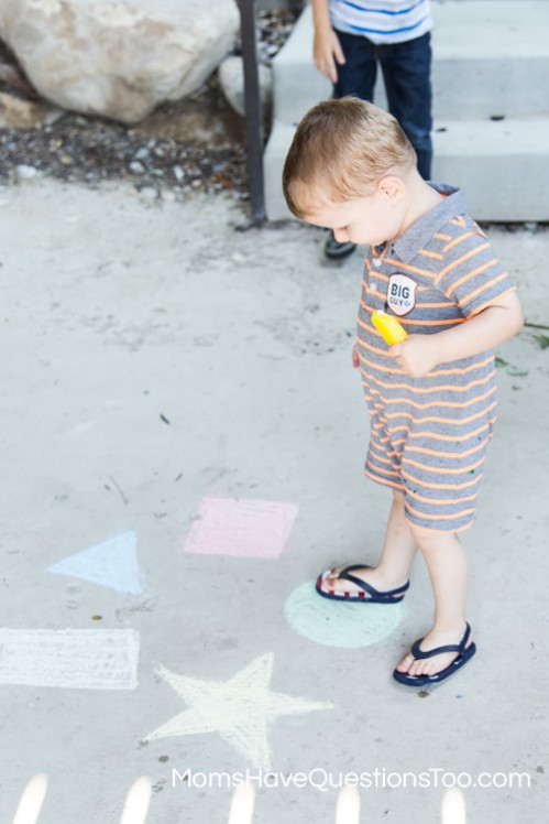 Fun toddler activity to help improve gross motor skills - jumping on colored chalk shapes - Moms Have Questions Too